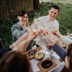 Foto S´INNVIERTEL Tourismus/Matthias Klugsberger: Gruppe junger Leute sitzt an einem gedecktem Tisch und stoßt an